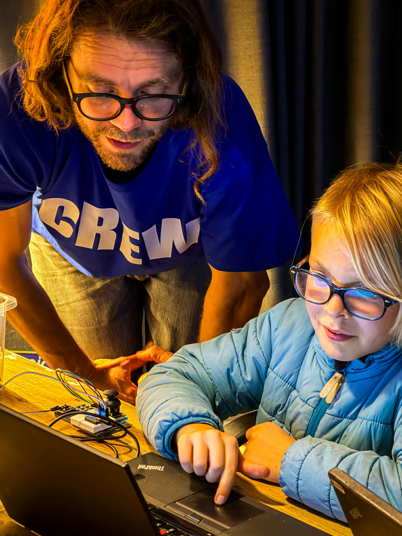 Karl teaching electronics to a child in a workshop